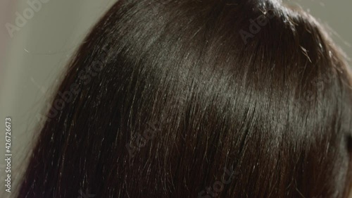 Charming brunette girl is combing her shiny thick well-groomed hair with her hands. Concept for organic shampoo and hair conditioner. Mask for easy combing
