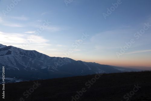 Landscape in the mountains at sunset. View of the misty hills hidden behind the oncoming darkness