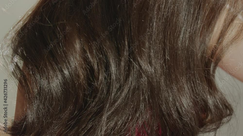 Beautiful brunette girl is combing her beautiful thick well-groomed hair with a comb. Concept of professional cosmetics for hair care in the salon and at home Beautiful brunette girl is combing her beautiful thick well-groomed hair with a comb. Concept of professional cosmetics for hair care in the salon and at home