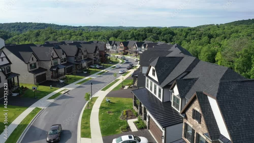Flying over a curving street in a new development American neighborhood with luxury single family homes 