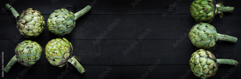 Fototapeta premium Fresh green artichokes on wooden board. Long banner