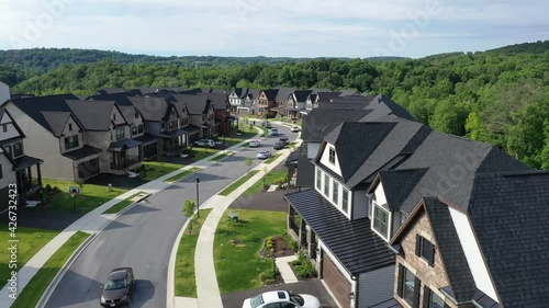 Flying over a curving street in a new development American neighborhood with luxury single family homes  photo