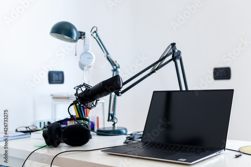 Microphone, laptop and headphone for home live streaming session. Tools for digital audience engagement activities such podcast, webinar, social media live session. Home working and smart working