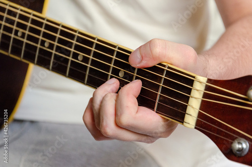 male fingers playing acoustics guitar strings