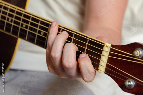 male fingers playing acoustics guitar strings
