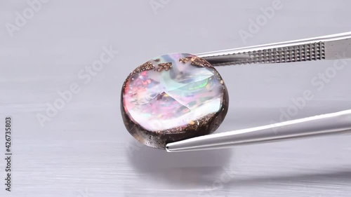 natural koroit bolder flash opal in the tweezers