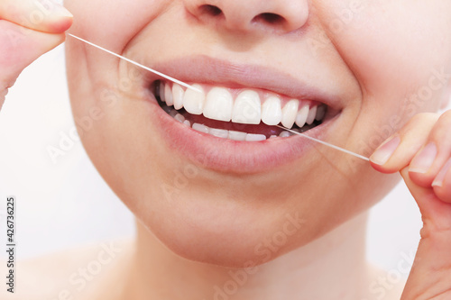 A cropped shot of a young beautiful woman flossing her teeth on a white background. Close-up. Dental concept