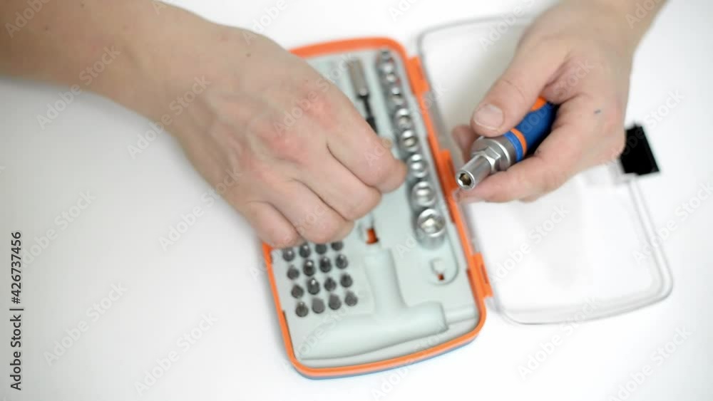 top view of male hand picking screwdriver bit from repair kit on isolated white background top view of male hand picking screwdriver bit from repair kit on isolated white background