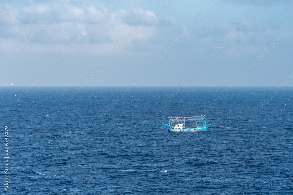 Small, blue fishing boat at open sea.
