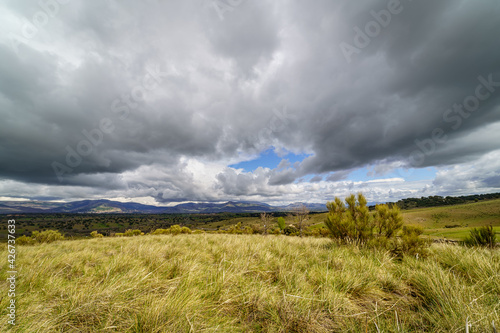 Dramatic sky of black clouds in the green field, wide angle view. Madrid. © josemiguelsangar