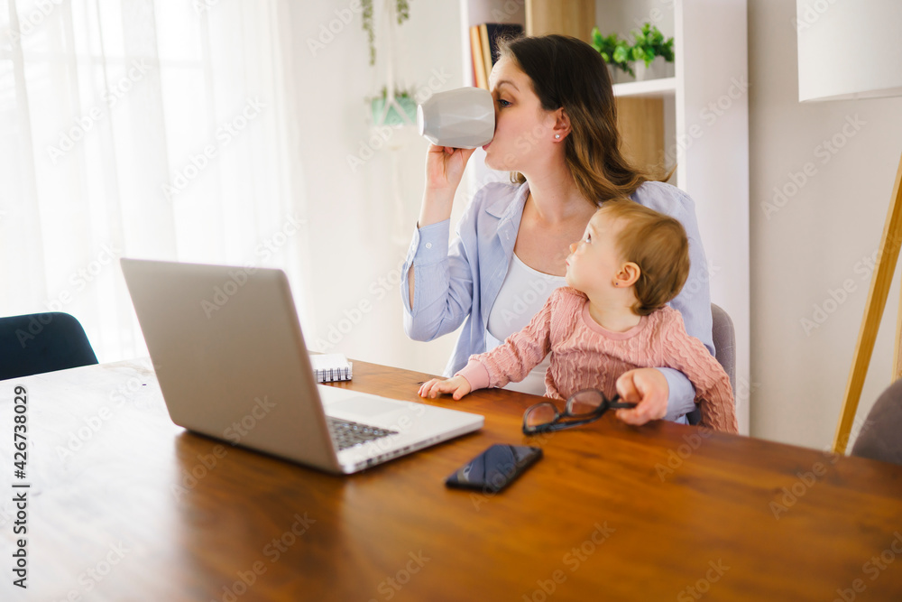 mother in kitchen home office with computer and her daugher