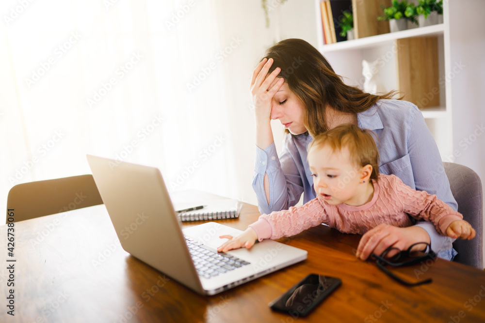 sad and frustrated mother in kitchen home office with computer and her daugher sad and frustrated mother in kitchen home office with computer and her daugher