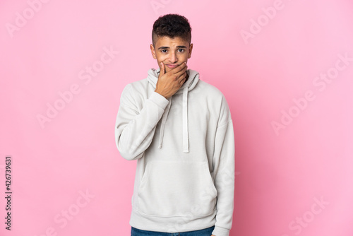 Young Brazilian man isolated on pink background having doubts