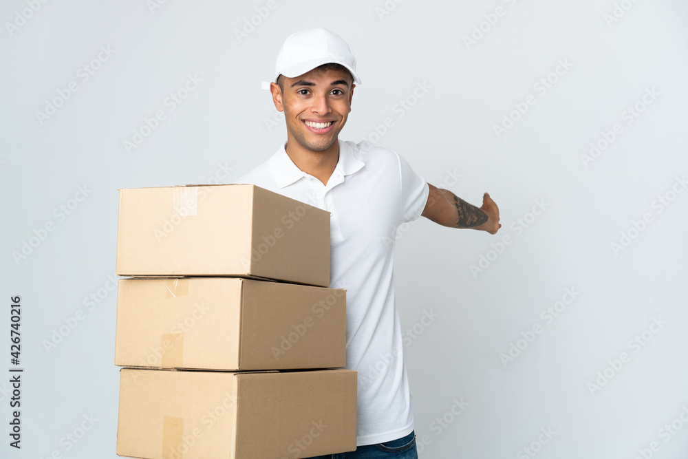 Delivery Brazilian man isolated on white background extending hands to the side for inviting to come Delivery Brazilian man isolated on white background extending hands to the side for inviting to come