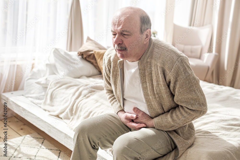 Elderly man with bellyache holding stomach with his hand