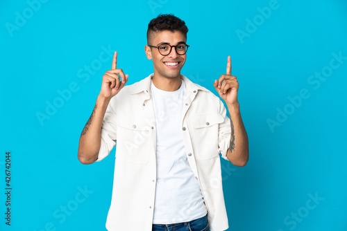 Young Brazilian man isolated on blue background pointing up a great idea