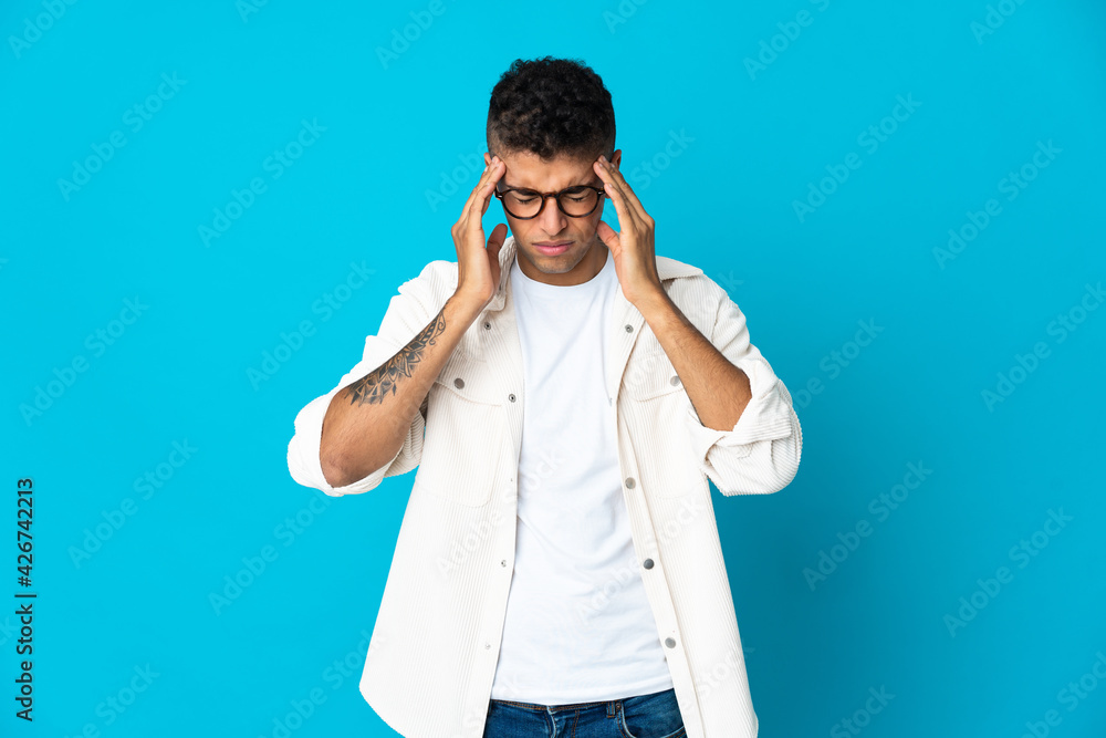 Young Brazilian man isolated on blue background with headache Young Brazilian man isolated on blue background with headache