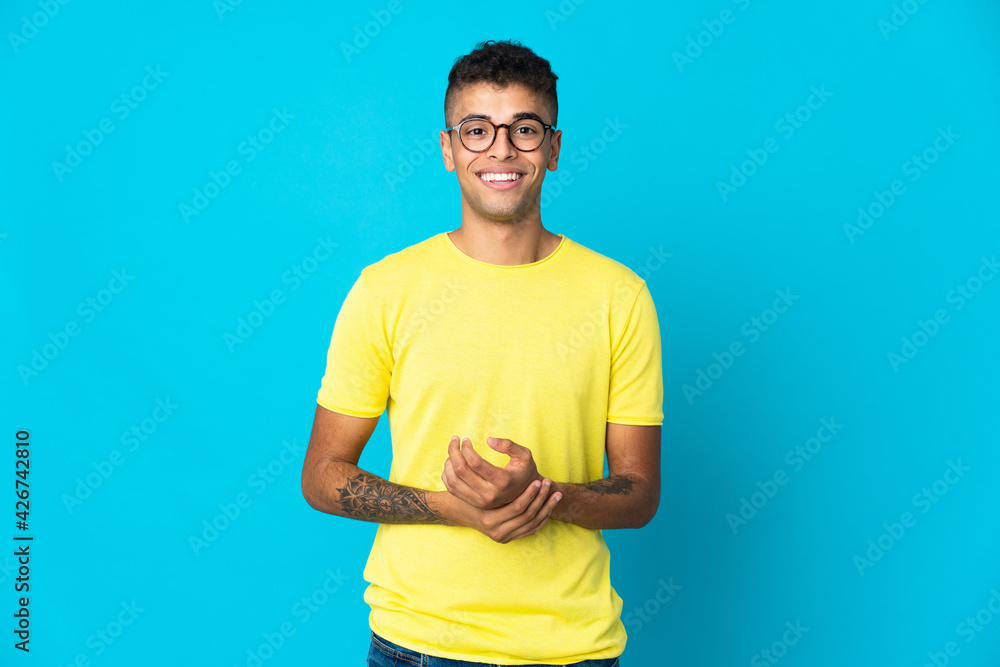 Young Brazilian man isolated on blue background laughing Young Brazilian man isolated on blue background laughing