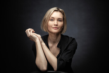 Beautiful middle-aged woman on a gray background in a black blouse.