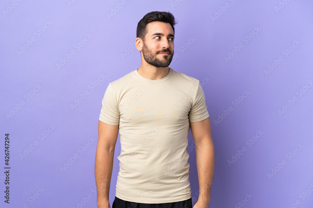 Young handsome man with beard over isolated background having doubts while looking side Young handsome man with beard over isolated background having doubts while looking side