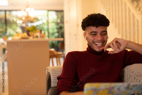 Happy young man with earbud headphones watching movie on laptop