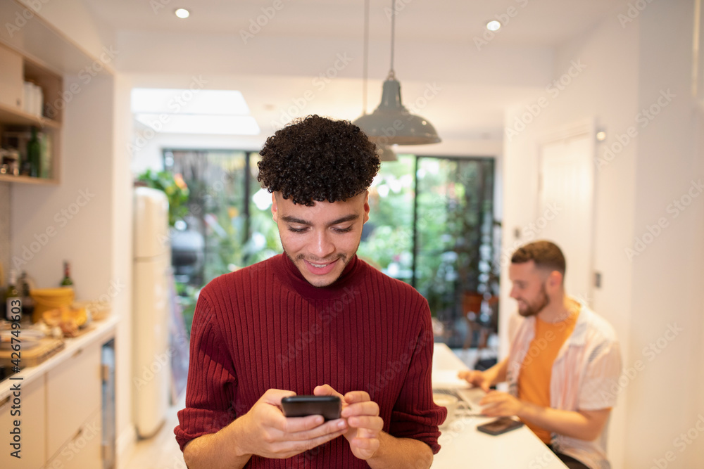 Young man using smart phone in kitchen Young man using smart phone in kitchen