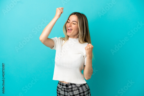 Young woman over isolated blue background celebrating a victory