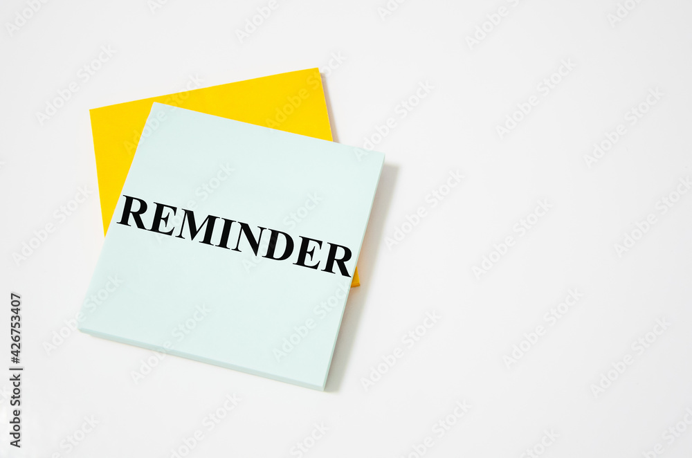 reminder text written on a white notepad with colored pencils and a yellow background reminder text written on a white notepad with colored pencils and a yellow background