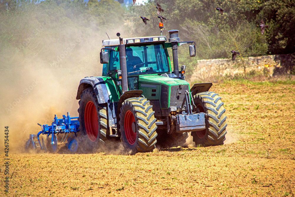 tractor plows a field on a farm in a village, agriculture tractor plows a field on a farm in a village, agriculture