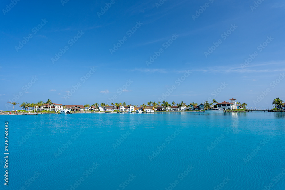 Blick auf den Hafen einer Insel auf den Malediven mit kleinen Häusern, Palmen und Booten im Hintergrund
