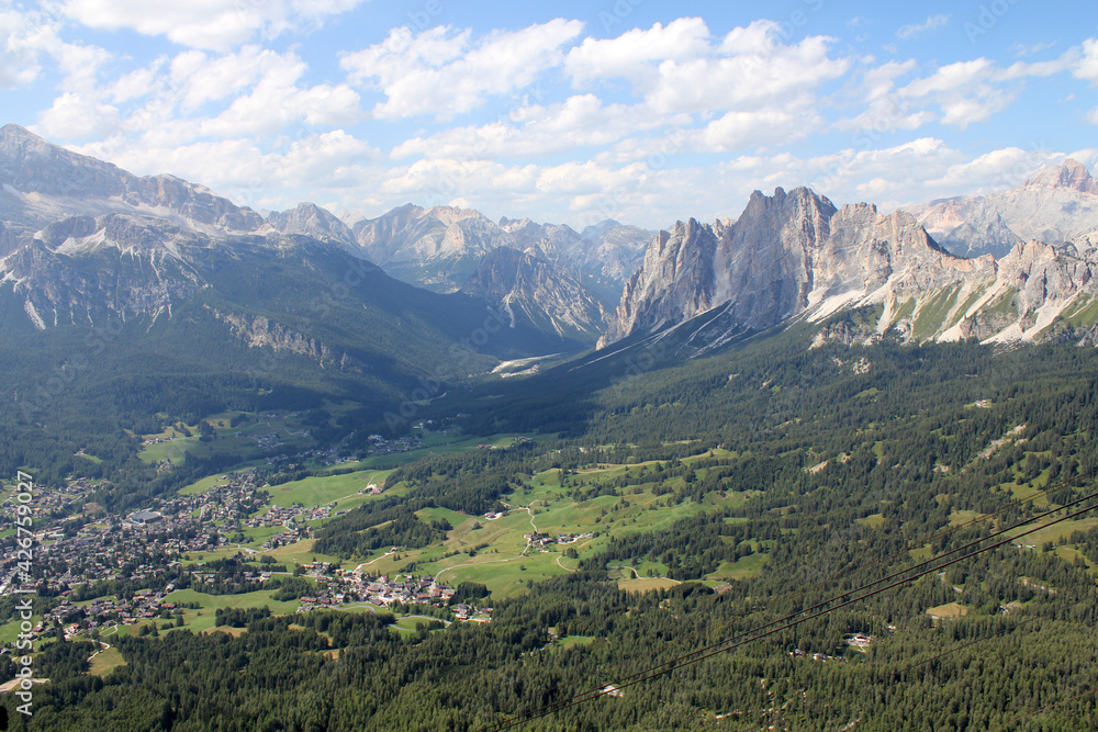 A beautiful sunny day in the mountains of Italy. Blue sky with clouds. Green meadows. Lots of greenery. Tourist route