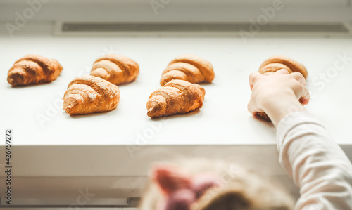 Fresh croissants on the white background. Little girls hand reaching out homemade pastry