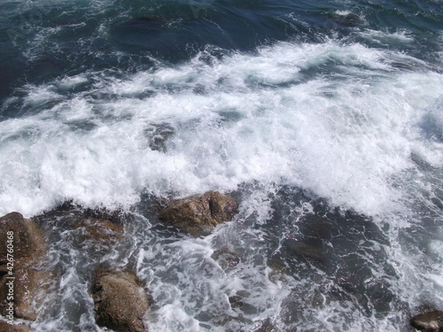 Sea waves  white foam hitting the rocky shore