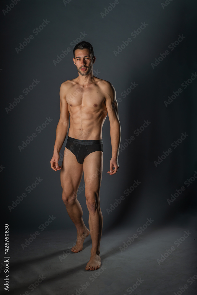 Naked young sexy man posing in black underwear in a studio Naked young sexy man posing in black underwear in a studio