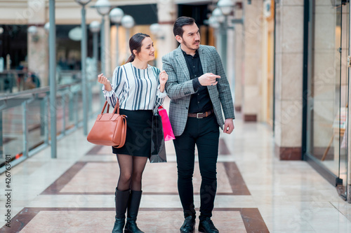Modern looking couple in a shopping mall  they are looking and pointing to the showcase