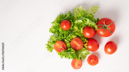 Juicy and ripe cherry tomatoes and green fresh lettuce on a white background. Top view. Copy space