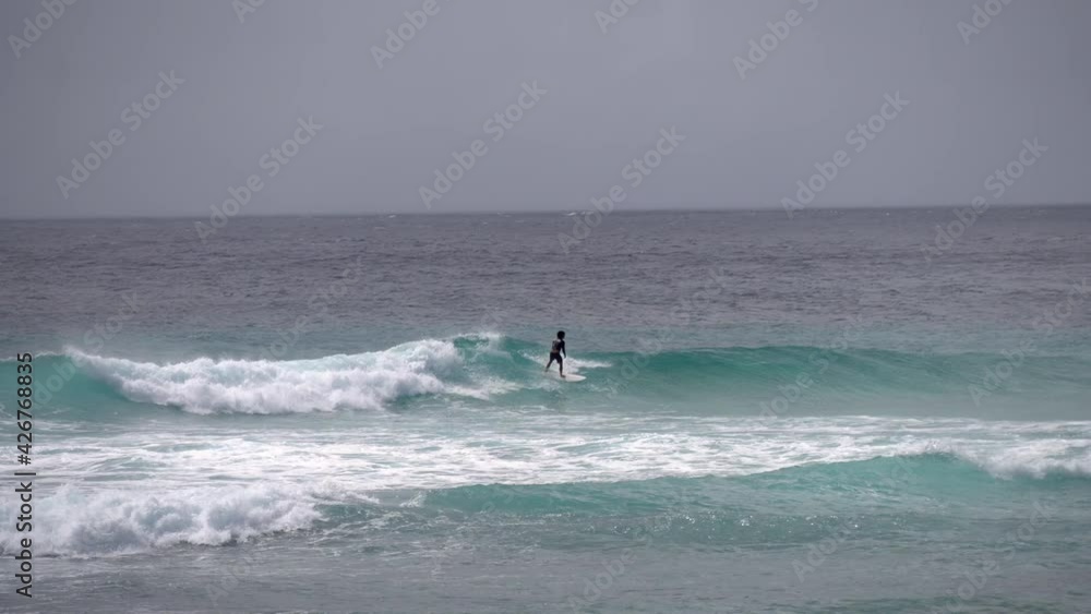 Surfer riding and turning with spray on blue ocean wave, surfing ocean lifestyle, extreme sports. Big waves with white foam in Hawaii. Pacific Ocean Surfer riding and turning with spray on blue ocean wave, surfing ocean lifestyle, extreme sports. Big waves with white foam in Hawaii. Pacific Ocean
