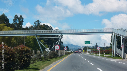 Puente peatonal sobre una vía recta entre campos