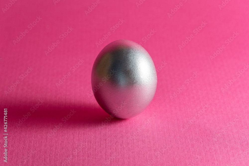 Silver egg on a dark pink background. Abstract Easter background
