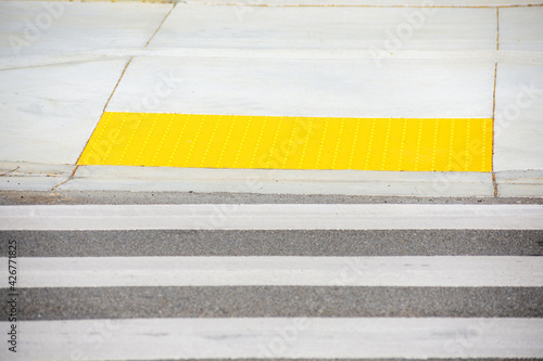 Pedestrian crossing leads to yellow detectable warning surface tactile paving. Selective focus.