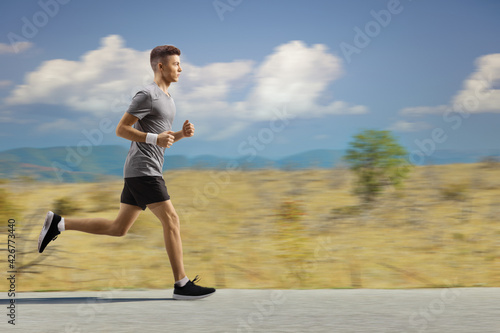 Young guy jogging in the countryside on an open road © Ljupco Smokovski