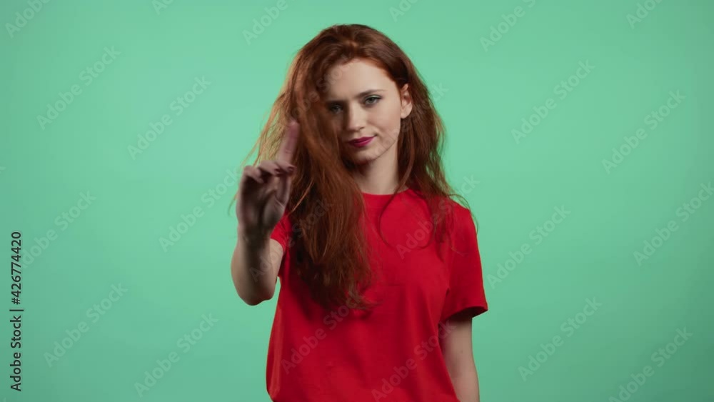 Portrait of serious woman showing rejecting gesture by stop finger sign. Girl isolated on green background. Portrait of serious woman showing rejecting gesture by stop finger sign. Girl isolated on green background.