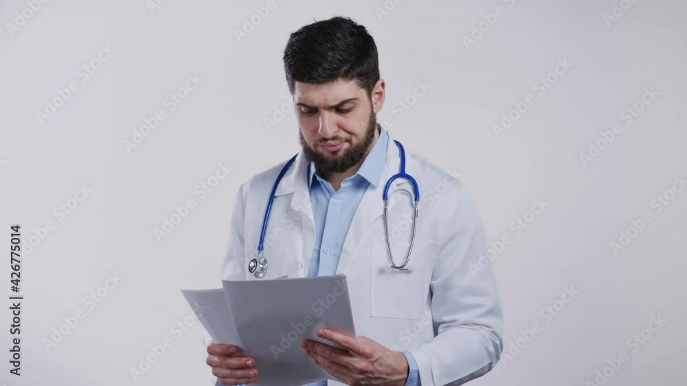 Satisfied doctor man in professional medical coat holding files papers isolated on white background. He nods his head approvingly to diagnosis. Doc with beard and stethoscope. Satisfied doctor man in professional medical coat holding files papers isolated on white background. He nods his head approvingly to diagnosis. Doc with beard and stethoscope.