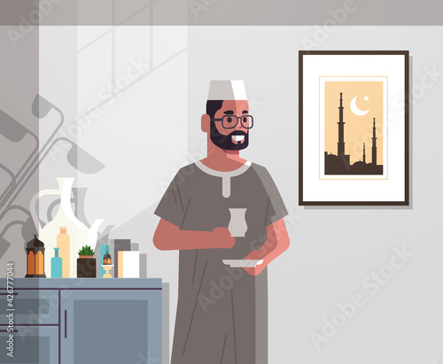 arabic man in traditional clothes drinking coffee celebrating ramadan kareem holy month modern living room interior flat vertical portrait © mast3r