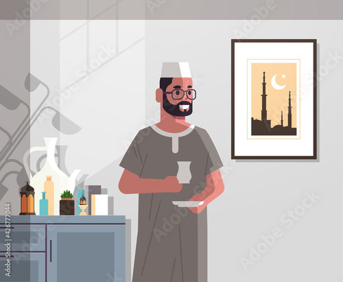 arabic man in traditional clothes drinking coffee celebrating ramadan kareem holy month modern living room interior flat vertical portrait