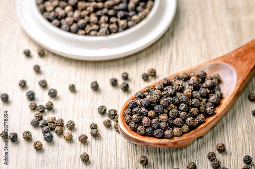 Black pepper seed in a wooden spoon on the table, spice used in cooking