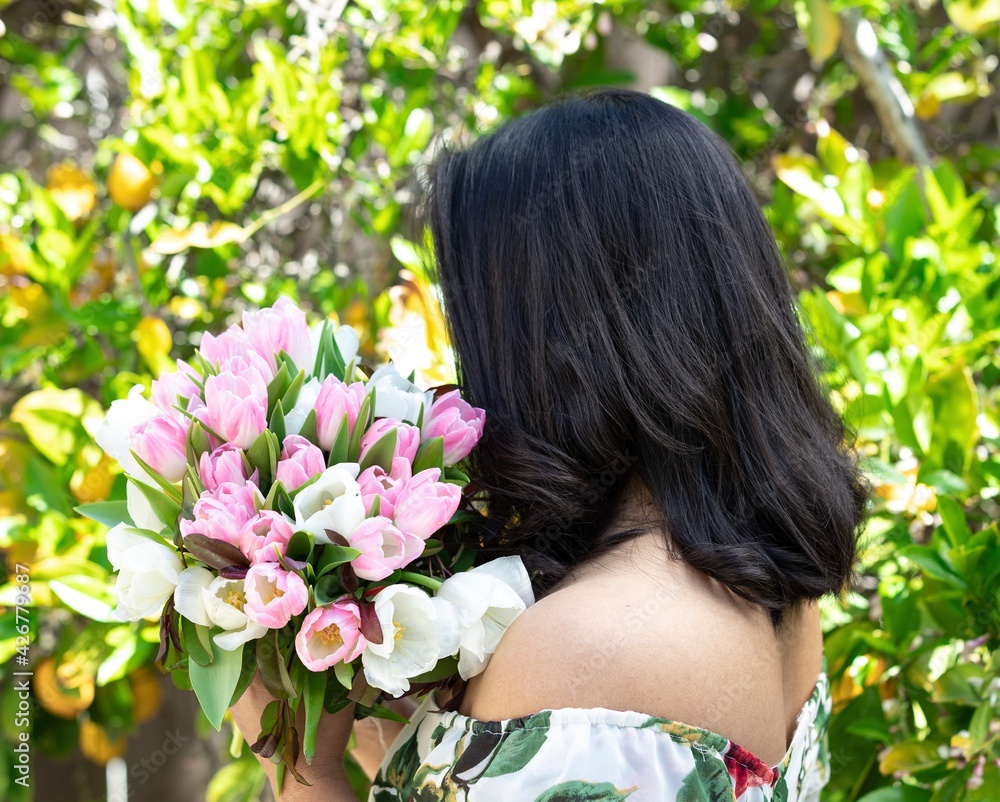Naklejka premium A young woman holding a bunch of tulip flowers