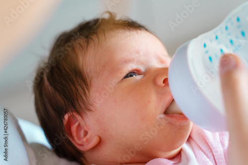 one week old caucasian baby bottle feeding artificial milk close up