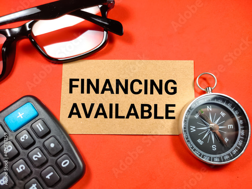 Selective focus of compass,calculator and glasses with text FINANCING AVAILABLE on red background.Business concept.
