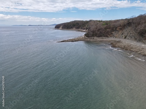 A pristine tropical beach in Costa Rica, with palm trees swaying in the breeze, crystal clear water, soft white sand, and vibrant wildlife in the surrounding rainforest.